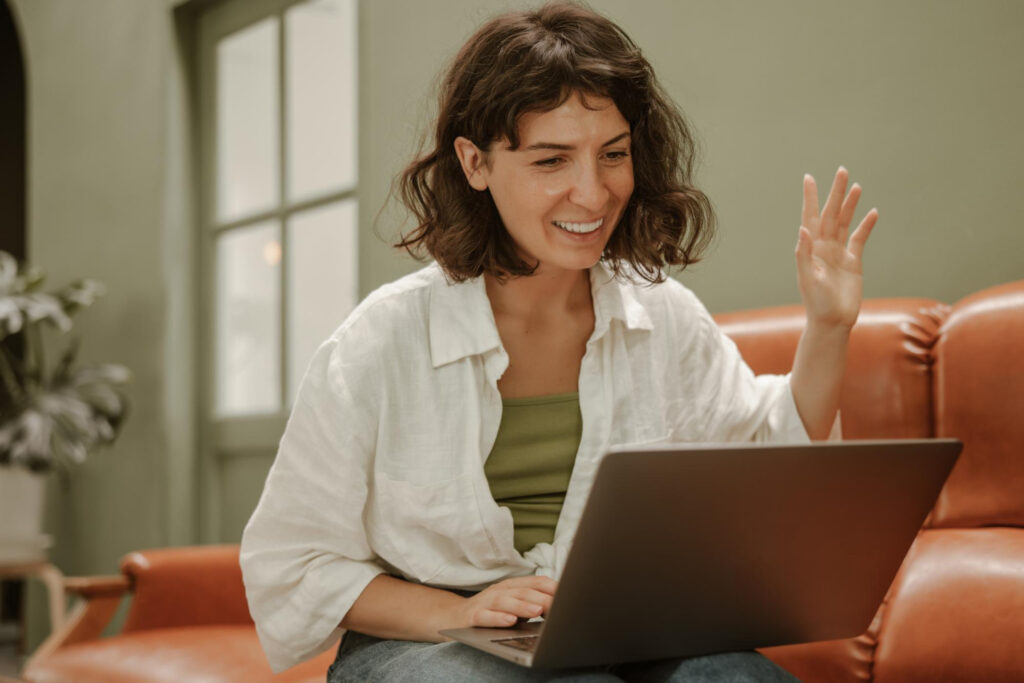 sesion virtual, mujer frente a la computadora levantando la mano